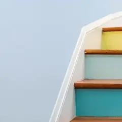 A young girl sits on colorful stairs, engrossed in a tablet, a bright future made possible by a Morgan Stanley 529 plan.