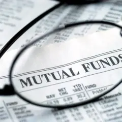 Glasses focus on "MUTUAL FUNDS" in a financial newspaper, hinting at investment research for a vanguard star fund.