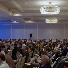 Attendees at the Morgan Stanley Laguna Conference listen intently in a large ballroom with ornate chandeliers.