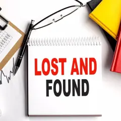 Searching for lost 401k accounts? This image shows a desk with financial documents, a calculator, and a notebook with "LOST AND FOUND" written on it, suggesting a search for forgotten assets.