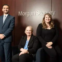Three professionals, including Monica Guerra, pose in front of the Morgan Stanley logo.