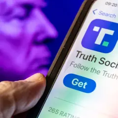 A hand hovers over a smartphone displaying the Truth Social app, with a purple, blurred image of a face in the background, perhaps hinting at the dwac stock price.