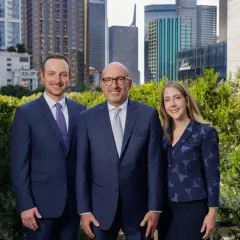 Alan Thomas Morgan Stanley: Three professionals in suits stand before a city skyline.