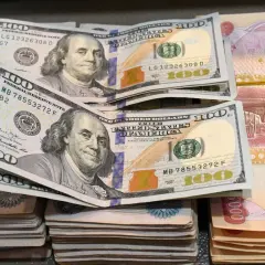 Stacks of US dollars and Iraqi dinars (IQD) are shown, hinting at forex trading.