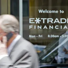 A man on the phone walks past a window displaying "Welcome to E*TRADE FINANCIAL." This image captures the moment before the Morgan Stanley E*TRADE acquisition.