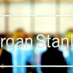 Glass doors with "Morgan Stanley" etched in white letters. Blurred figures are visible inside, suggesting a busy office environment.
