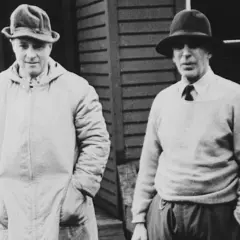 Two men in hats, one in a long coat, the other in a sweater, possibly representing the early days of Morgan Stanley founder.