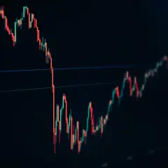 A stock trading chart shows red and green candlesticks on a dark background, indicating market fluctuations.