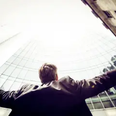 A triumphant Morgan Stanley vice president, arms outstretched, celebrates success against a backdrop of modern skyscrapers.