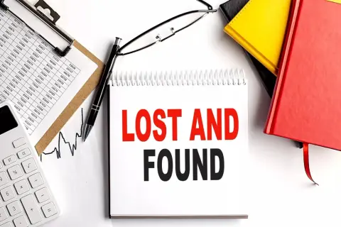 Searching for lost 401k accounts? This image shows a desk with financial documents, a calculator, and a notebook with "LOST AND FOUND" written on it, suggesting a search for forgotten assets.