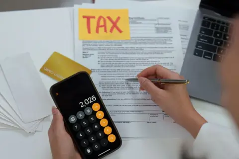 Calculating 401k tax rate implications with a calculator and tax forms.