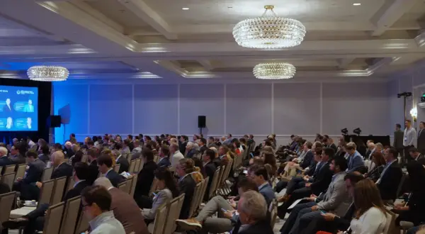 Attendees at the Morgan Stanley Laguna Conference listen intently in a large ballroom with ornate chandeliers.
