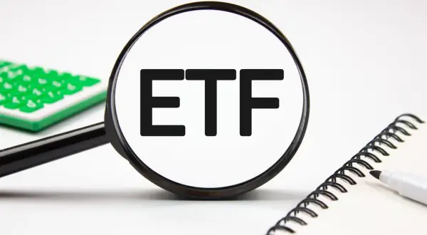 Magnifying glass focuses on "ETF" text, hinting at stock analysis. A calculator and notebook are nearby.