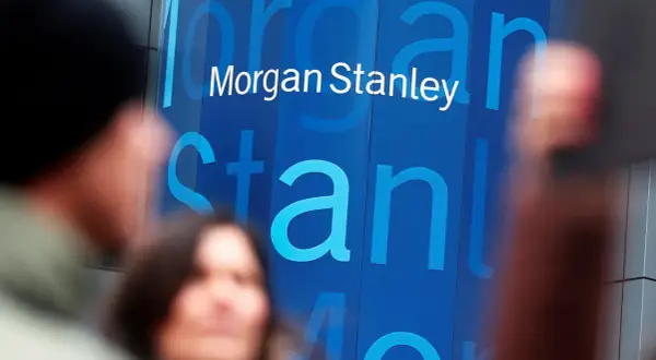 Blurred figures stand before a blue building with the "Morgan Stanley" logo. Investors anticipate the latest Morgan Stanley earnings report.