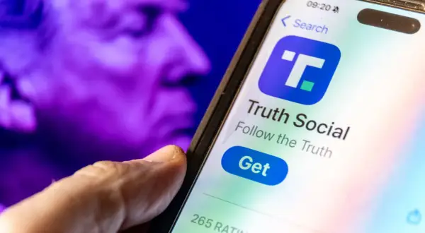 A hand hovers over a smartphone displaying the Truth Social app, with a purple, blurred image of a face in the background, perhaps hinting at the dwac stock price.