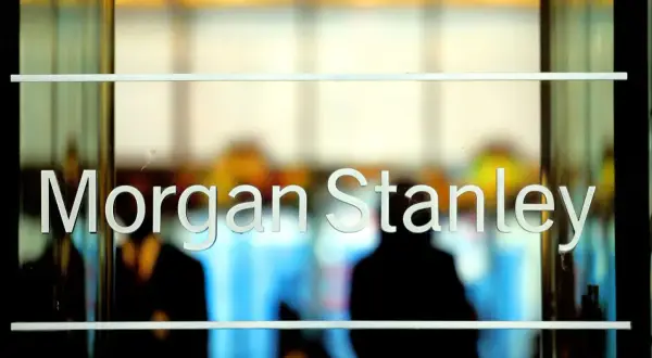 Glass doors with "Morgan Stanley" etched in white letters. Blurred figures are visible inside, suggesting a busy office environment.