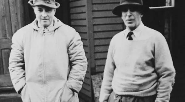 Two men in hats, one in a long coat, the other in a sweater, possibly representing the early days of Morgan Stanley founder.