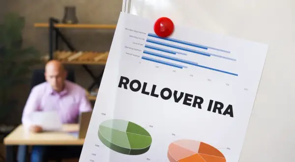 Paper titled "ROLLOVER IRA" with charts and graphs, showing financial data. Charitable contributions from IRAs are no longer allowed.