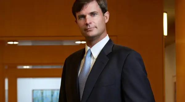 Dennis Lynch, a distinguished professional at Morgan Stanley, poses confidently in a dark suit and light blue patterned tie.
