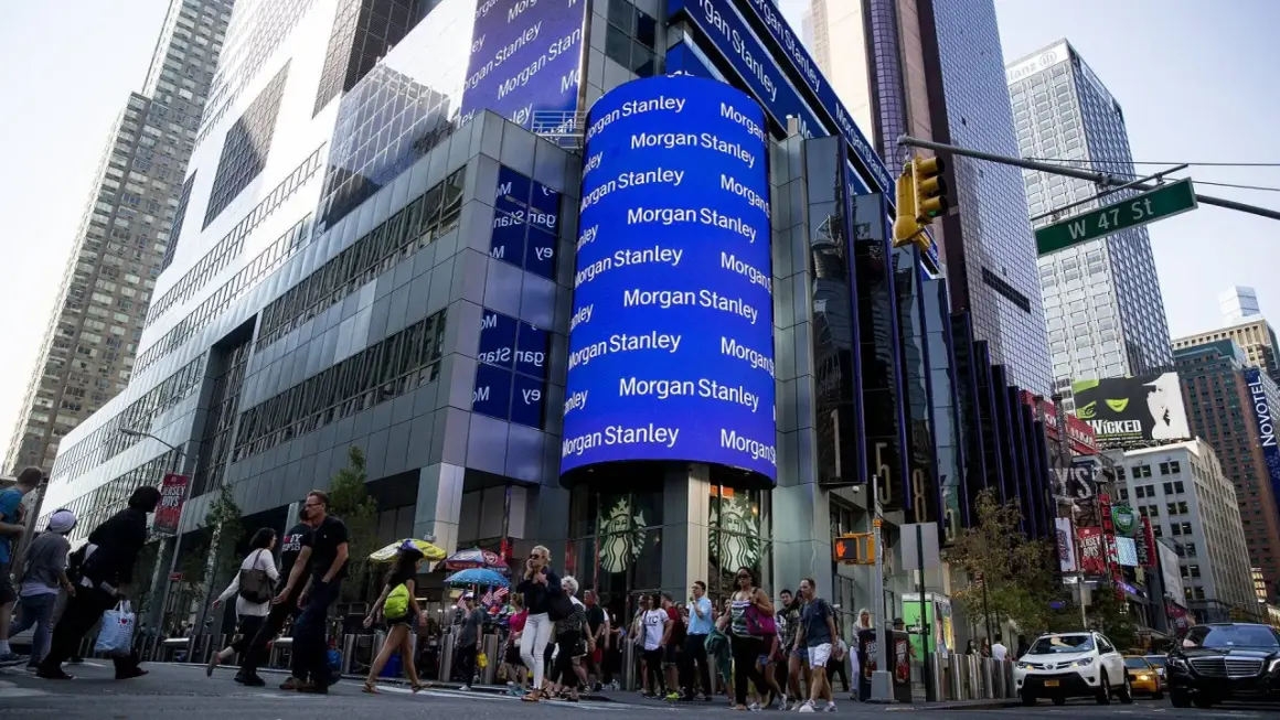 A large blue digital billboard displays "Morgan Stanley" repeatedly, highlighting their significant assets under management in this bustling Times Square scene.
