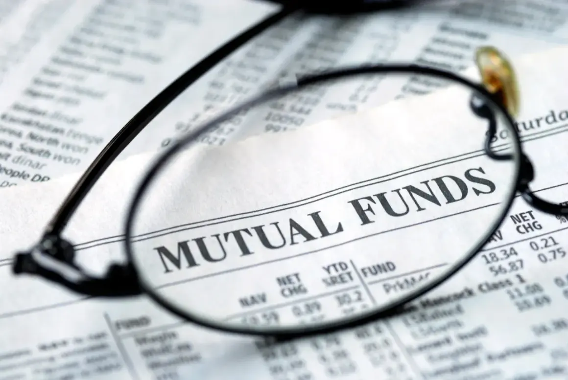 Glasses focus on "MUTUAL FUNDS" in a financial newspaper, hinting at investment research for a vanguard star fund.