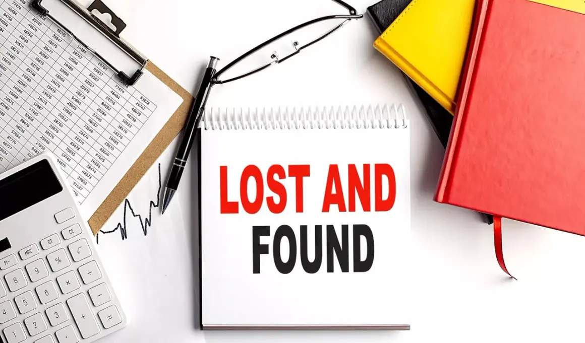 Searching for lost 401k accounts? This image shows a desk with financial documents, a calculator, and a notebook with "LOST AND FOUND" written on it, suggesting a search for forgotten assets.