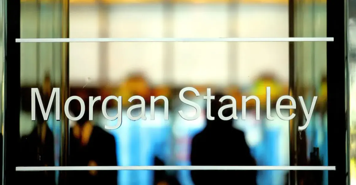 Glass doors with "Morgan Stanley" etched in white letters. Blurred figures are visible inside, suggesting a busy office environment.