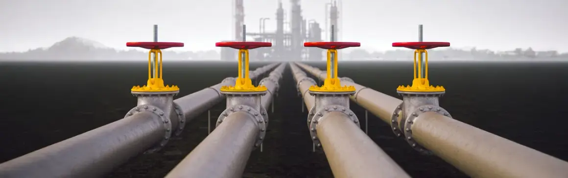 Rows of industrial pipes with red and yellow valves stretch towards a hazy refinery, symbolizing Morgan Stanley infrastructure.