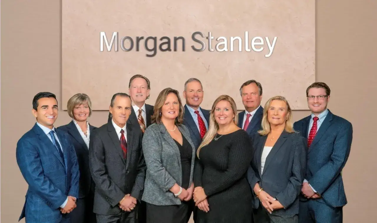 A team of professionals, including a Morgan Stanley vice president, poses for a photo in front of the company's logo.