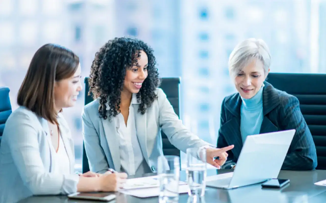 The investment team collaborates, with one member pointing at a laptop screen.