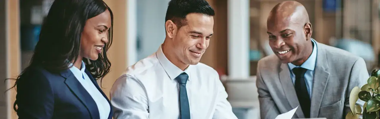 Three smiling professionals discuss a document, perhaps reviewing Morgan Stanley ETFs for a client's portfolio.