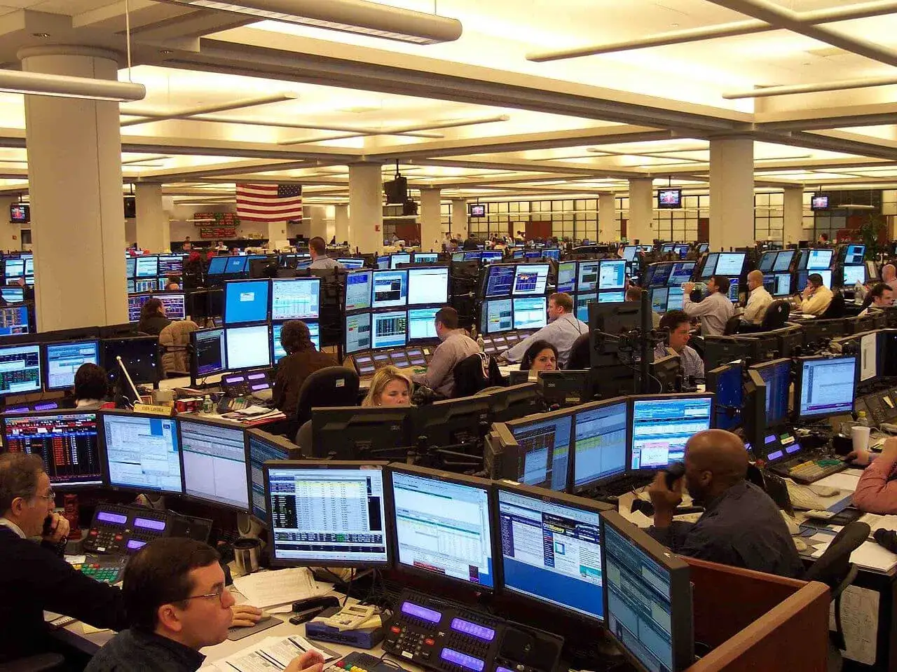A busy trading floor with many people working at computers, engaged in sales and trading activities.