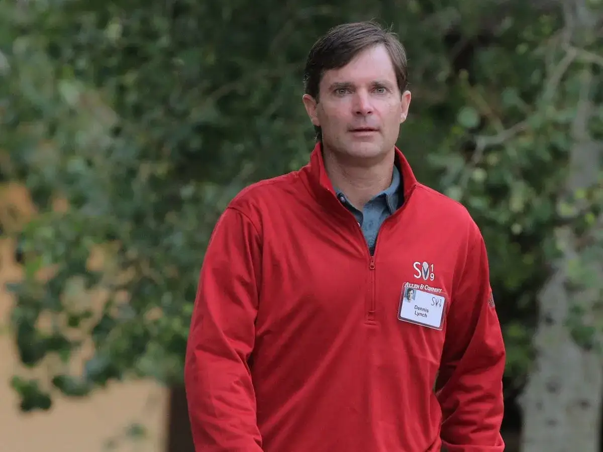 Dennis Lynch, wearing a red quarter-zip with an Allen & Company logo, appears to be attending a conference, perhaps related to his work at Morgan Stanley.