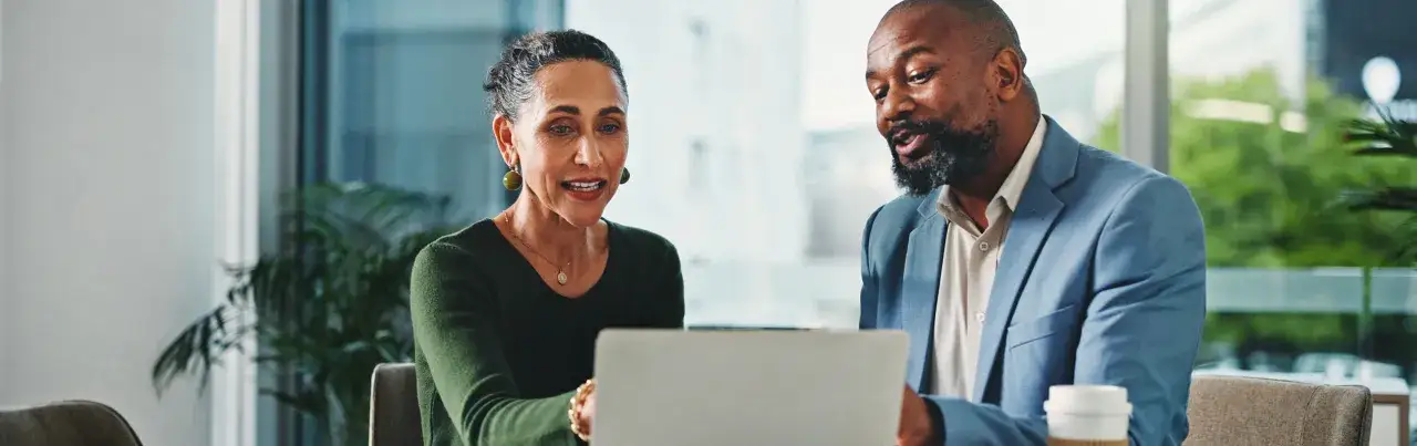 Two professionals discuss a laptop, perhaps reviewing data for a Morgan Stanley IPO.