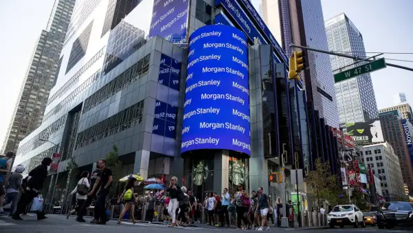 A large blue digital billboard displays "Morgan Stanley" repeatedly, highlighting their significant assets under management in this bustling Times Square scene.