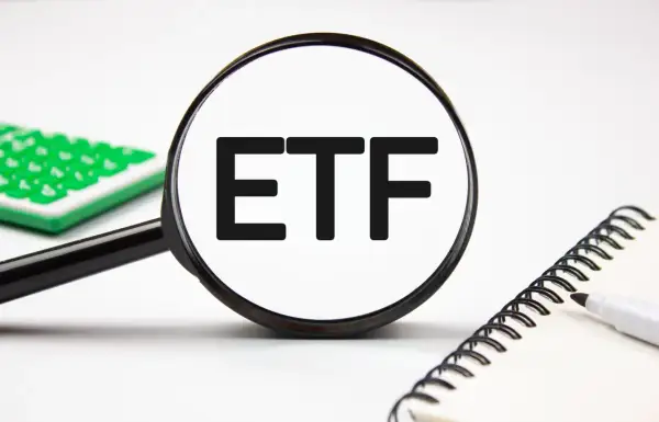 Magnifying glass focuses on "ETF" text, hinting at stock analysis. A calculator and notebook are nearby.