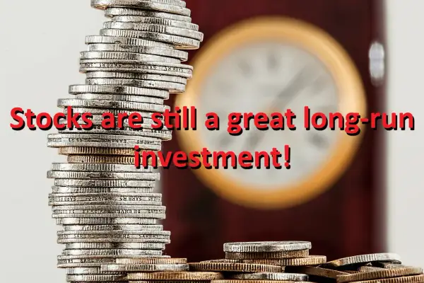 Stacks of coins with the text "Stocks are still a great long-run investment!" overlaid. The image suggests that despite fluctuations, the vtinx stock price can be a solid long-term investment.