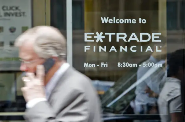 A man on the phone walks past a window displaying "Welcome to E*TRADE FINANCIAL." This image captures the moment before the Morgan Stanley E*TRADE acquisition.