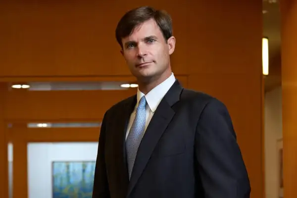 Dennis Lynch, a distinguished professional at Morgan Stanley, poses confidently in a dark suit and light blue patterned tie.